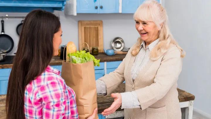 Une auxiliaire de vie fait les courses avec une personne âgée