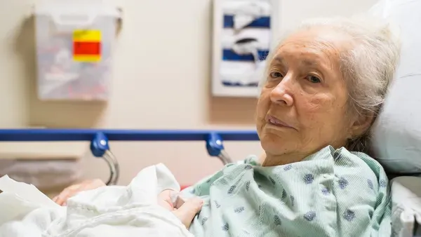 Vieille femme malade qui regarde la caméra dans une lit d'hôpital