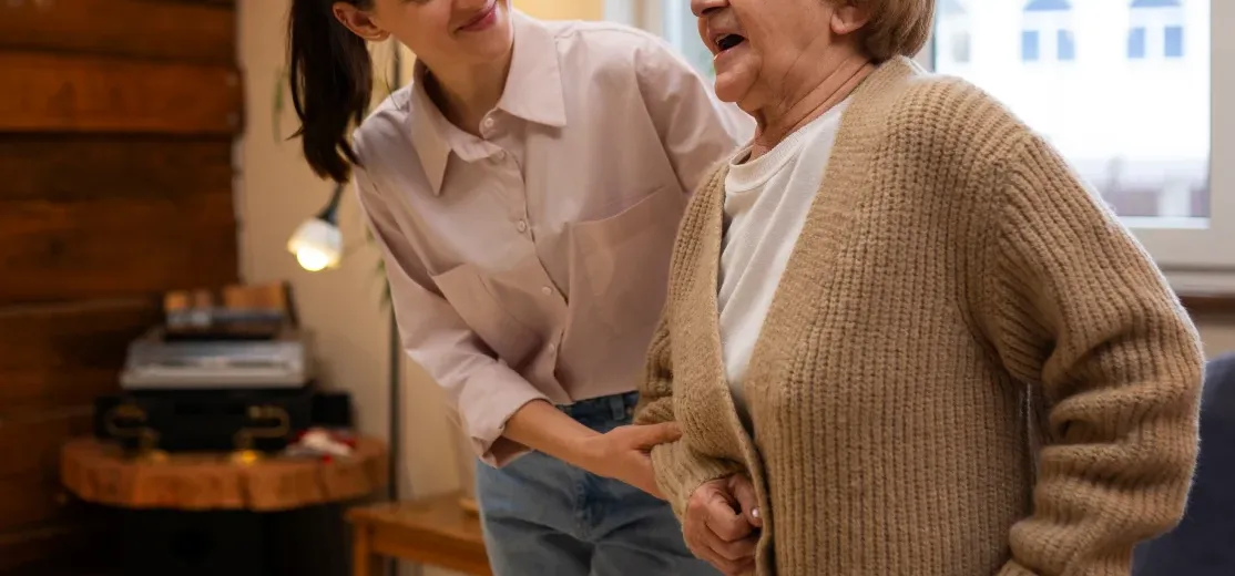 une dame de compagnie aide une personne âgée à se déplacer chez elle