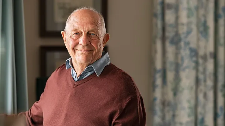 Portrait d’un homme âgé souriant chez lui